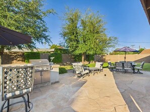 Eine Terrasss mit Grill, Sitzgelegenheit und Blick auf den Garten.