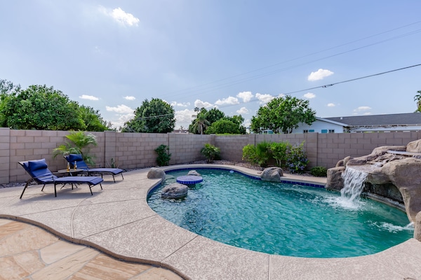 Stunning backyard retreat featuring a private pool with a waterfall, sun loungers, BBQ grill, outdoor seating, Smart TV, and an outdoor dining area.