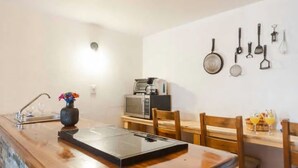 Een keuken met een houten aanrecht, een magnetron en een spoelbak. Er staan stoelen en een vaas met bloemen op het aanrecht.