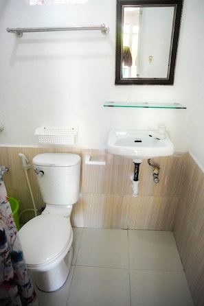 Un baño con inodoro, lavamanos y espejo.