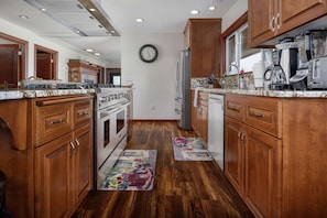 A kitchen with wooden cabinets, stainless steel appliances, and a clock on the wall. - Single Level Ranch Layout, Huge Patio, Surrounded by Vineyards, Free Tastings, Foosball and Fire-Pit (Dayton)