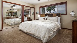 A bedroom with a large bed, a ceiling fan, a window with a view, and a mirror. - Single Level Ranch Layout, Huge Patio, Surrounded by Vineyards, Free Tastings, Foosball and Fire-Pit (Dayton)