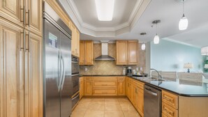 Een moderne keuken met houten kastjes, roestvrijstalen apparatuur en een betegelde achterwand.