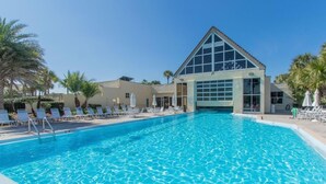 A swimming pool with lounge chairs and umbrellas, a building with a triangular roof, and palm trees. - Great St. Augustine beach vacation rental at a family friendly price! (Saint Augustine)