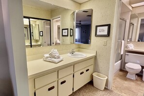 Une salle de bain avec un lavabo, un miroir et des toilettes.