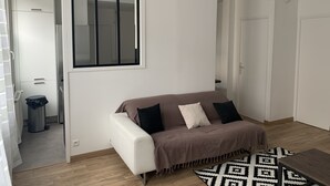 Un salon moderne avec un canapé blanc, un tapis à motifs et un plancher en bois.