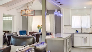 A modern kitchen with white cabinets, a dining area with leather chairs, and a hanging light fixture. - Sedona Splendor: A luxurious 3BR home in West Sedona with stunning red rock views. (Sedona)