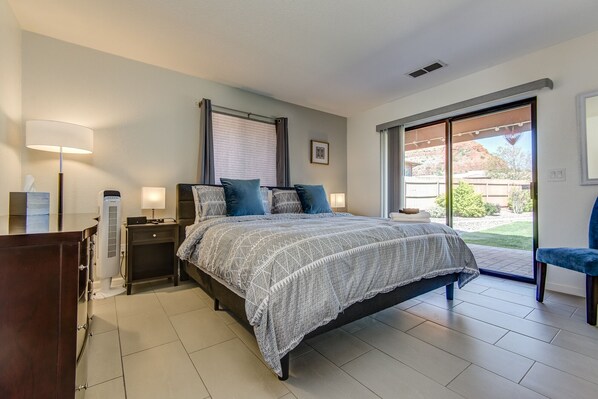 A bedroom with a bed, bedside lamps, a heater, a nightstand, and a view of the outdoors.