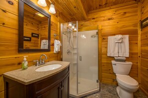 A wooden cabin bathroom with a granite sink, a glass-enclosed shower, and a toilet. - Secluded Luxury 2 Bdrm Log Cabin,Hot Tub,Theatre Rm,Assn Lake,WiFi,Offsite Pool (Sevierville)