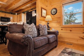 A wooden interior with a leather sofa, a clock, and a window.