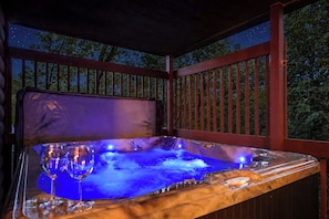 A hot tub with a glass enclosure, surrounded by a wooden deck with railings.
