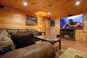 A cozy living room with a fireplace, a television, and a sofa with patterned cushions.