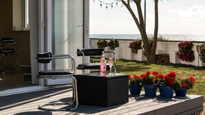 Una terrazza con mobili da esterno, una bottiglia e piante in vaso.