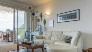 A modern living room with a white leather sofa, a wooden coffee table, and a glass door leading to an outdoor area. - Beautiful private villa for 8 people with hot tub, WIFI, A/C, TV, terrace and pets allowed (Santa Marinella)