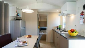 Una cocina compacta con comedor, refrigerador, estufa y ventana.