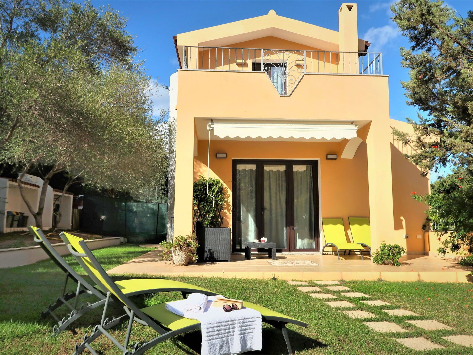 Un bâtiment à deux étages doté d’un balcon, d’une terrasse couverte et d’un petit espace extérieur aménagé avec une table et des chaises.