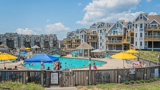A pool area with a wooden fence, a lifeguard tower, and a sign indicating no lifeguard on duty.