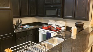 Una cocina con armarios de madera oscura, una estufa blanca, un microondas y una cafetera.