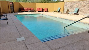 Una piscina con sillas de descanso y un muro de piedra.