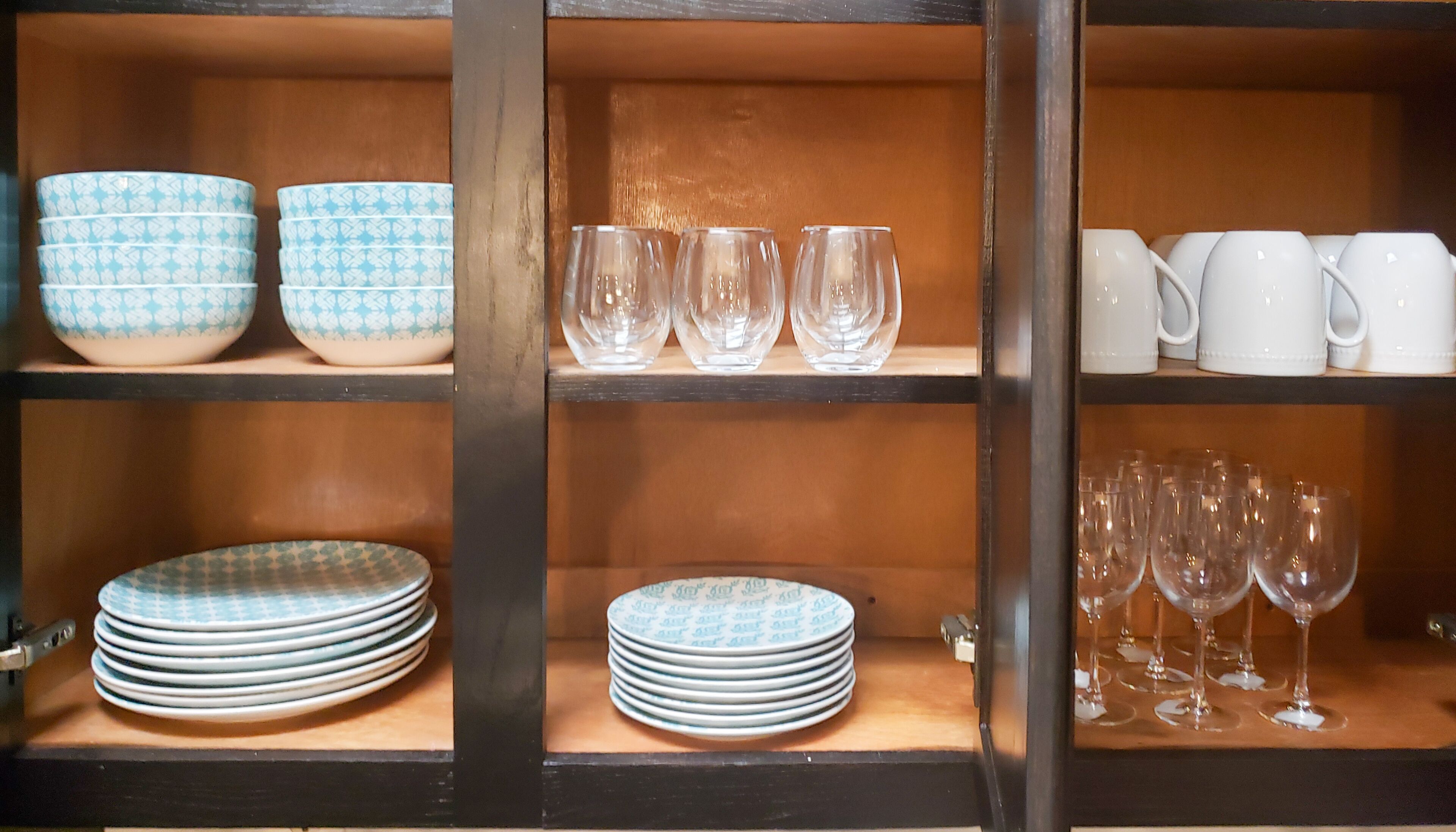 Un mueble de cocina con estantes que contienen platos, cuencos, vasos y tazas.