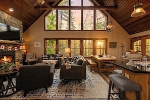 Un interior acogedor con chimenea, ventanas amplias, zona de comedor y cocina.