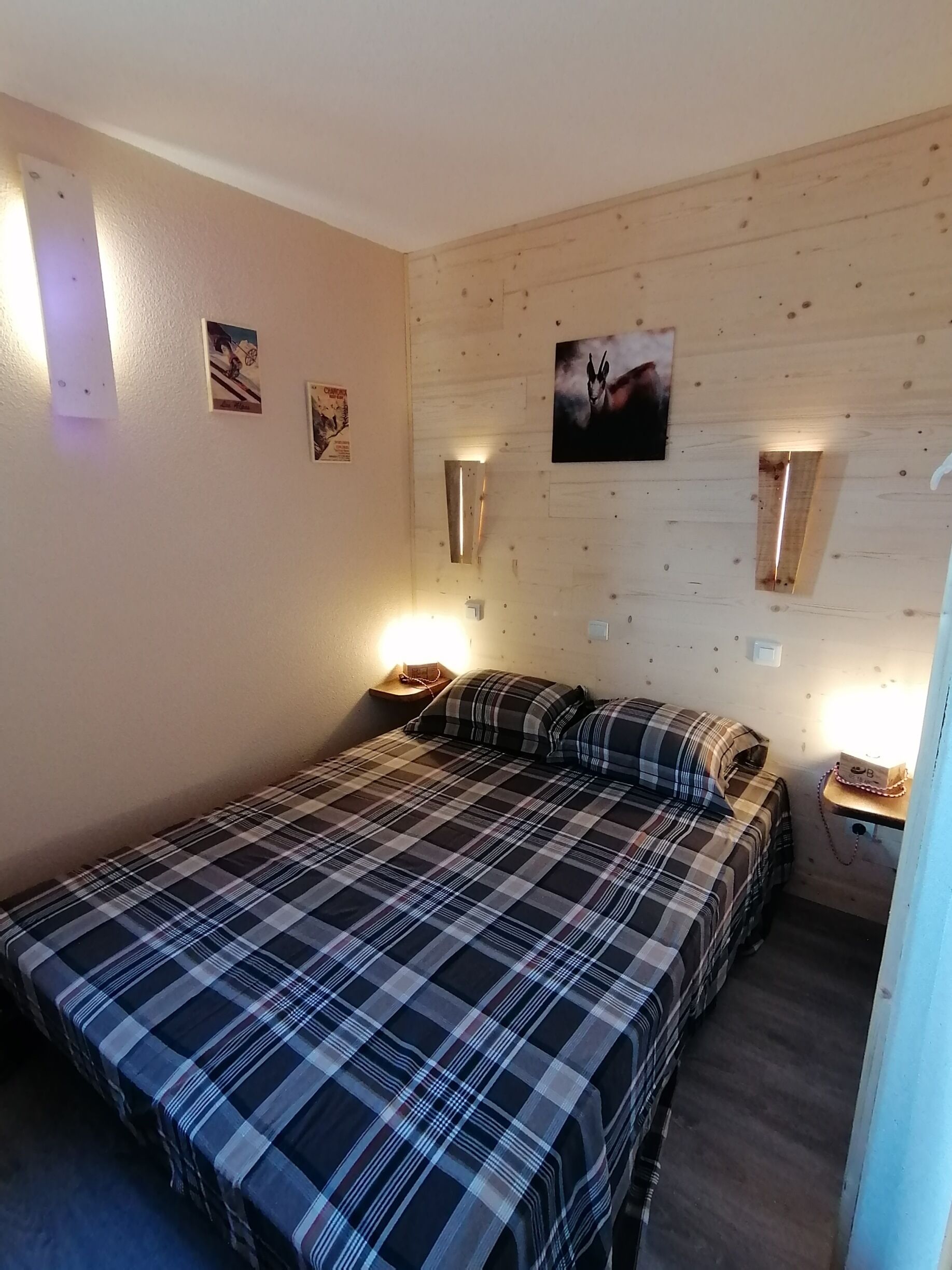 Een slaapkamer met een bed, twee nachtkastjes en wandlampen.