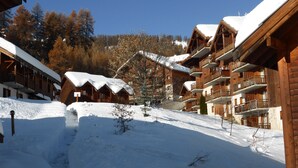 A snow-covered lodge with wooden architecture, multiple balconies, and a clear sky. - SOUTH ALPES APARTMENT PUY SAINT VINCENT 1800 M Ski resort summer / winter (Puy-Saint-Vincent)