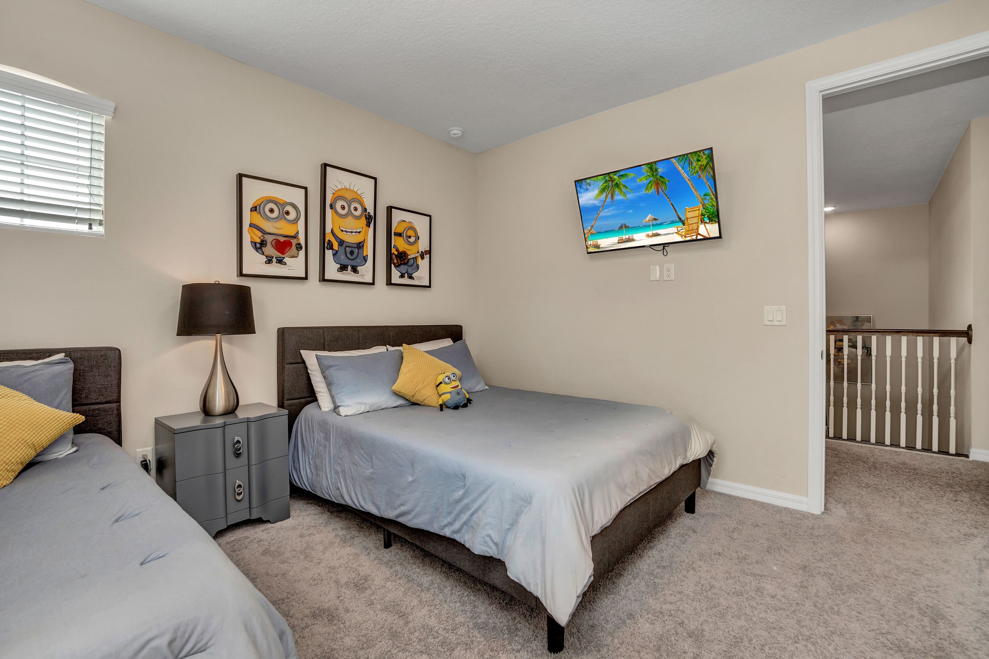 Un dormitorio con dos camas, una mesita de noche, una lámpara y un televisor en la pared.