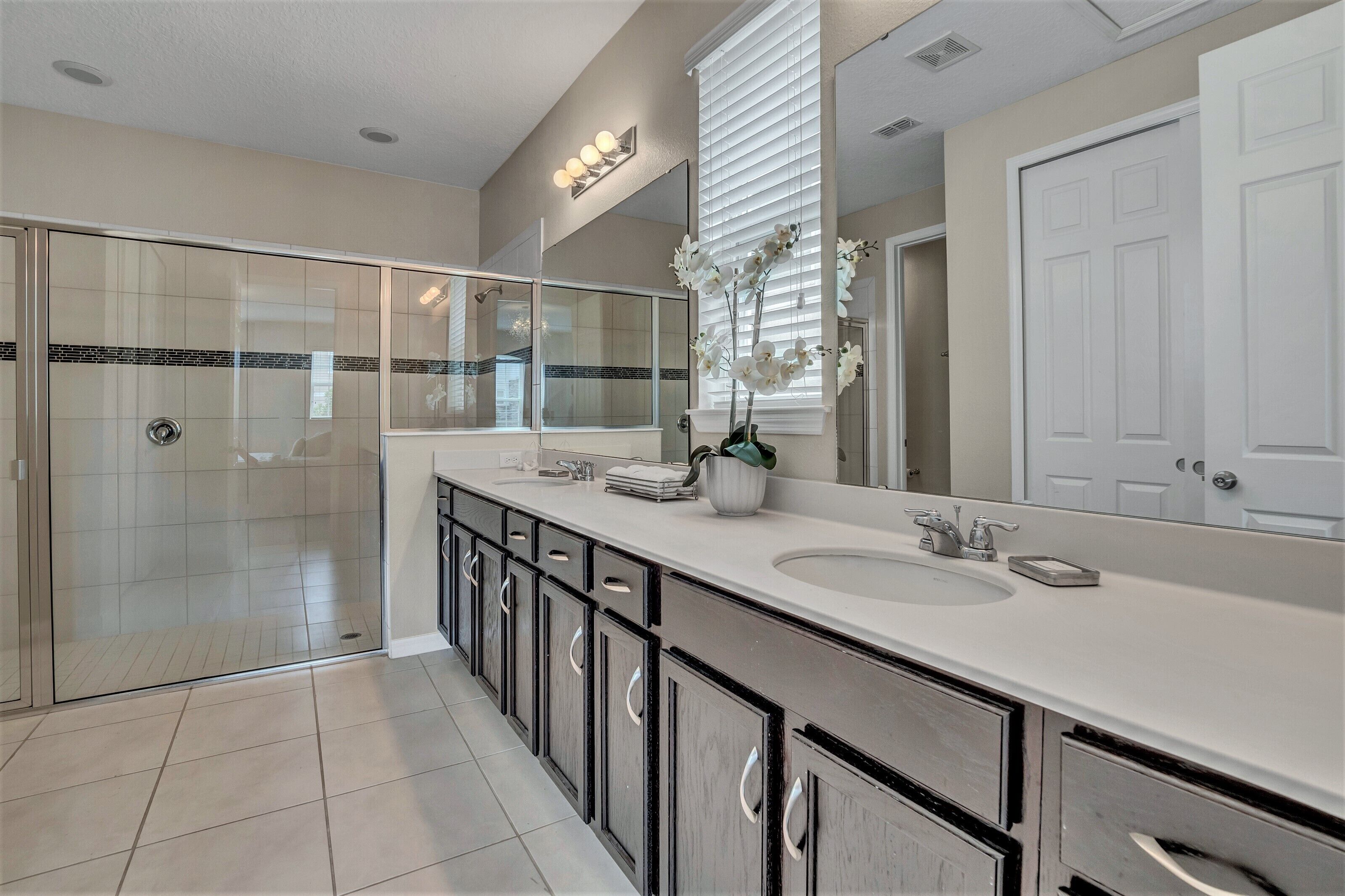 A modern bathroom with a glass-enclosed shower, a large mirror, and a white sink.