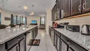 A modern kitchen with dark wooden cabinets, granite countertops, and stainless steel appliances.
