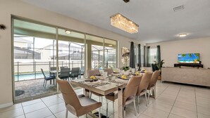 A spacious dining area with a large table set for six, surrounded by modern chairs.