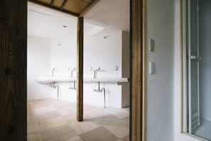Un baño moderno con dos lavamanos, tuberías visibles y suelo de madera.