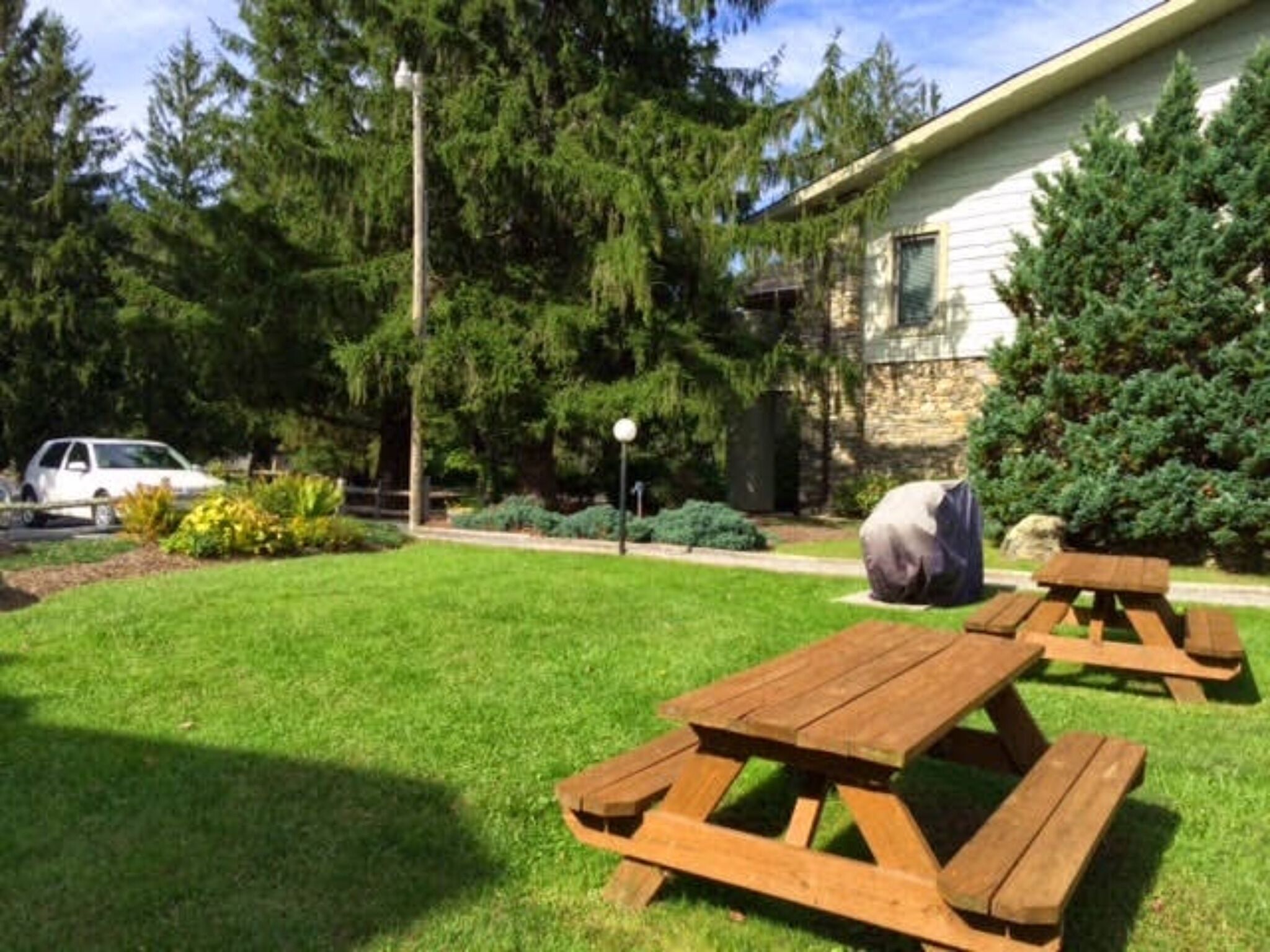 A grassy area with picnic tables and a stone building in the background.