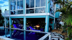 A two-story building with a swimming pool, a flag, and a stone pathway. - NO HURRICANE IMPACT!!! Private/Luxury/BeachView/Pool/Spa Steps to Sand! Balcony (Bradenton Beach)