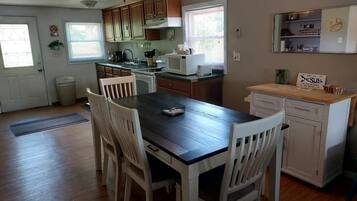 A kitchen with wooden cabinets, a microwave, and a dining table with chairs.