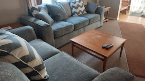Ein Wohnzimmer mit einem grauen Sofa, einem Holztisch und einer Lampe.