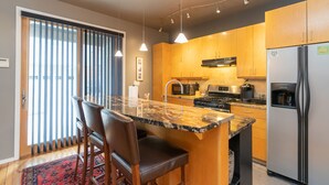 Une cuisine moderne avec des meubles en bois, un plan de travail en granit et des appareils électroménagers en acier inoxydable.