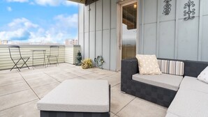 Une terrasse sur le toit avec un canapé aux motifs noir et blanc, une petite table et une chaise.