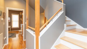 Un escalier moderne avec des marches en bois et des rampes blanches, menant à l’étage supérieur.