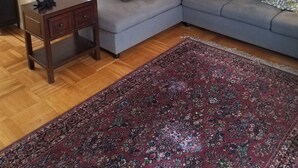 A living room with a grey sectional sofa, a small wooden table, a patterned rug, and a mirror on the wall. - Beautiful House with Panoramic SF Bay Views (San Francisco)