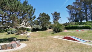 A park with a winding path, benches, and a small red and blue play area. - New house 350m from the beach in Cléder. Rated 3 stars. (Cléder)