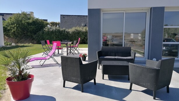 An outdoor patio with wicker furniture, a dining table, and chairs. - New house 350m from the beach in Cléder. Rated 3 stars. (Cléder)