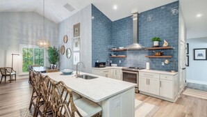 Een moderne keuken met een centraal eiland, witte kasten en een blauwe achterwand.