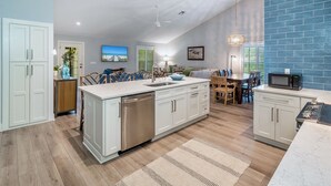 Een moderne keuken met een centraal eiland, witte kasten en een blauwe bakstenen accentmuur.