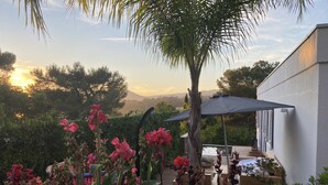 Un patio con vistas a la montaña, rodeado de vegetación exuberante y plantas en flor.