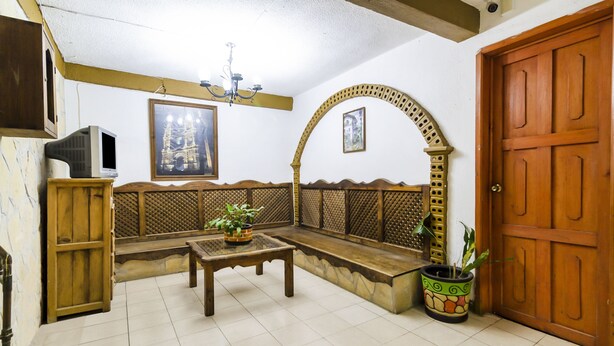 A living room with a wooden bench, a small table, and a potted plant. - OYO Hotel La Luna (San Cristóbal de las Casas)