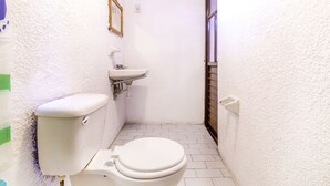 A small, white bathroom with a toilet, sink, and a window. - OYO Hotel La Luna (San Cristóbal de las Casas)