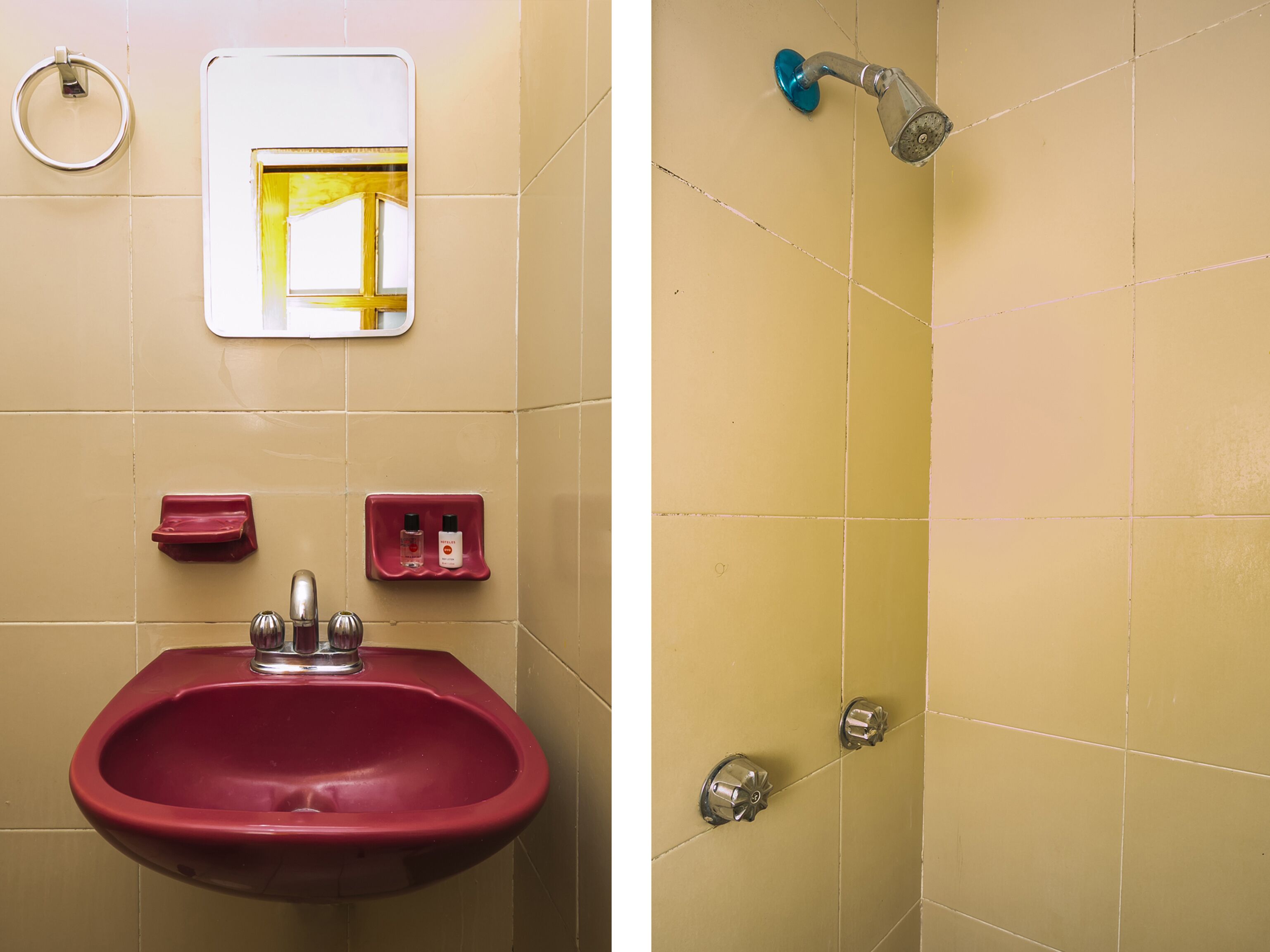 Un baño con un lavabo rojo, un espejo, un toallero y una ducha con pomo azul.