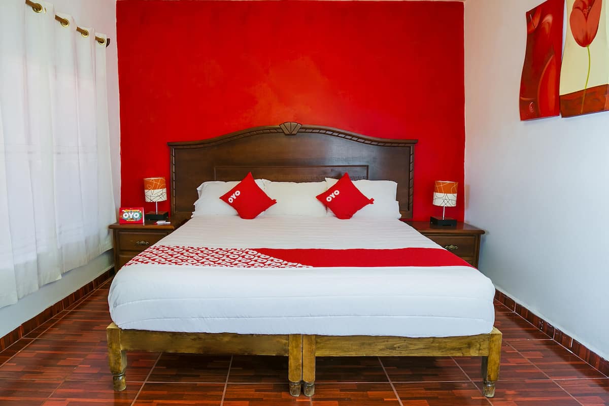 Ein Hotelzimmer mit einem großen Bett, roten Wänden und einem Holzkopfschild.