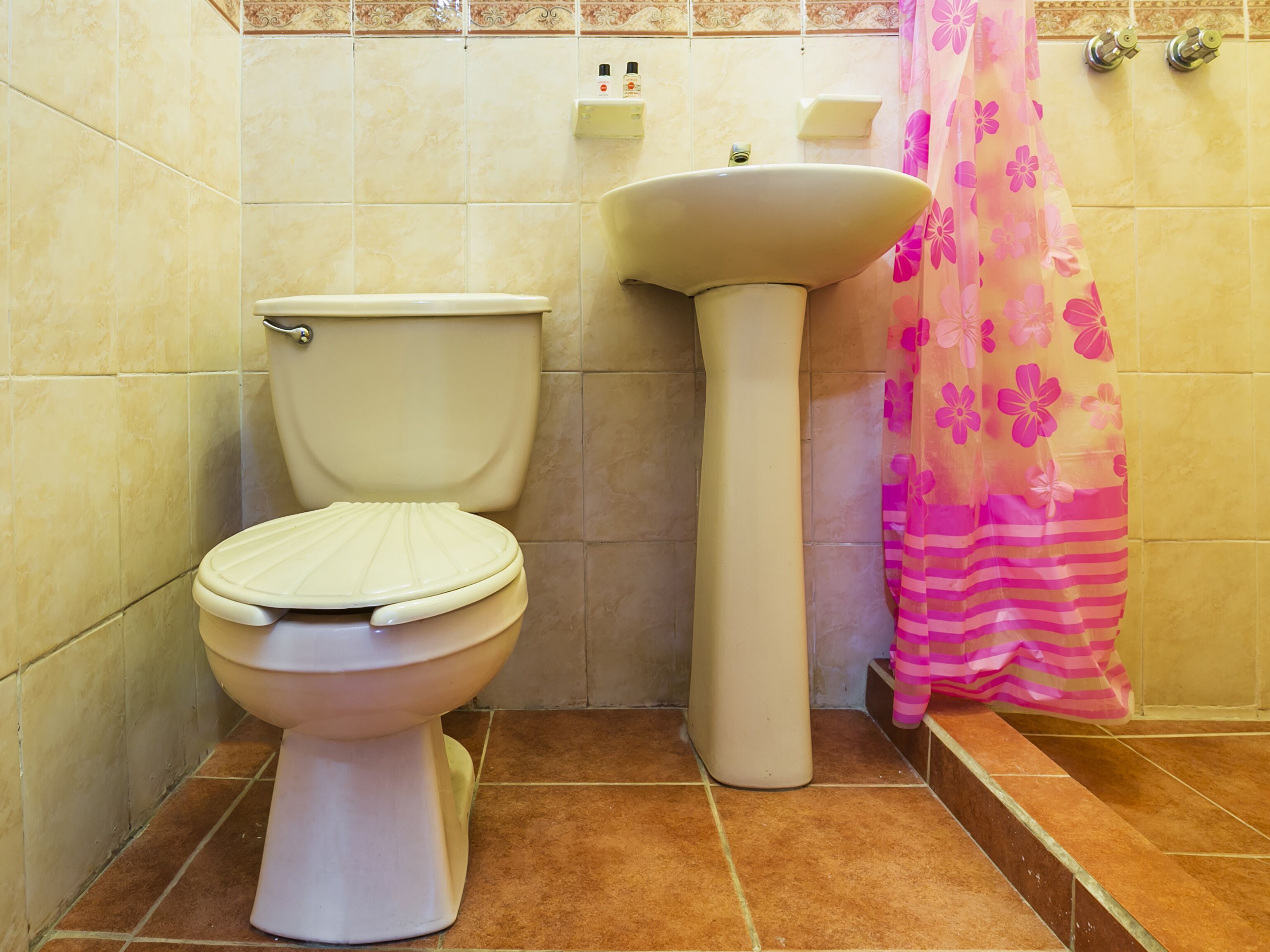 Un baño con inodoro, lavamanos y cortina de ducha.
